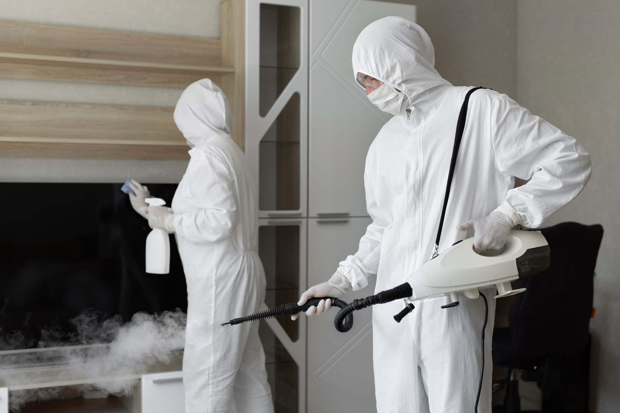 People in hazmats doing disinfection in home, with hot steam disinfection.